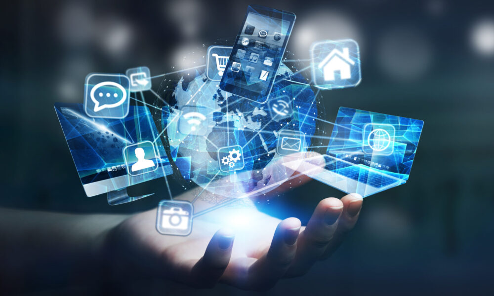 Mano di donna sopra alla quale fluttuano dispositivi tecnologici connessi e icone di applicazioni su un pianeta Terra digitale che rappresentano i servizi, prodotti e connessioni che offre Trevigroup