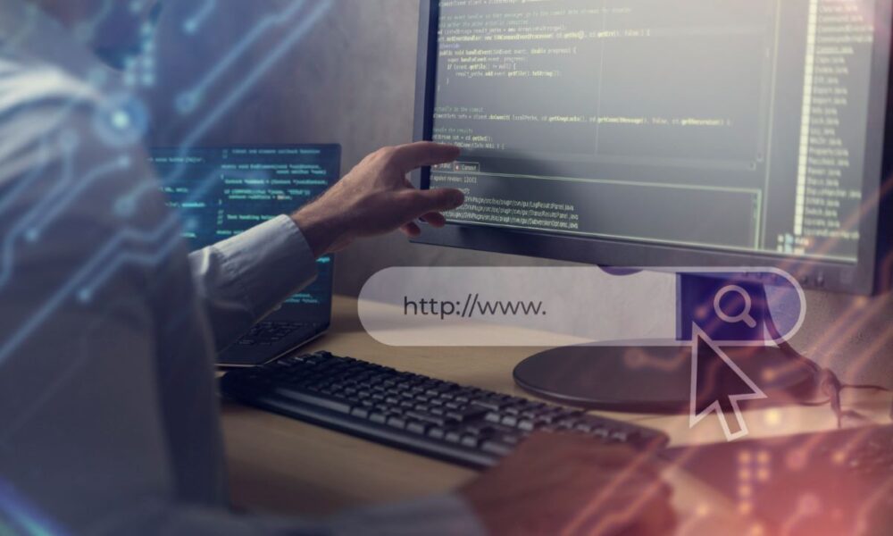 Immagine di una persona di spalle intenta a scrivere codice di sviluppo per un sito web la cui barra di ricerca è in primo piano in trasparenza.