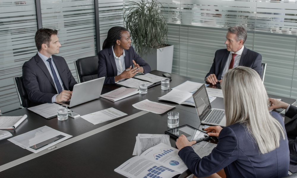 Foto di una consulenza in azienda a cui stanno partecipando quattro persone sedute ad un tavolo in un ufficio.