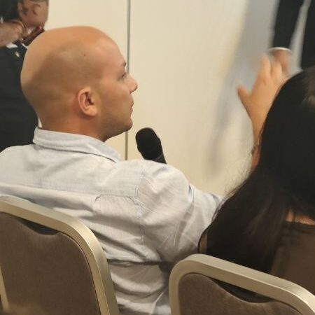 Partecipante dell’evento Generazione AI interviene con il microfono durante il confronto con i relatori in sala.